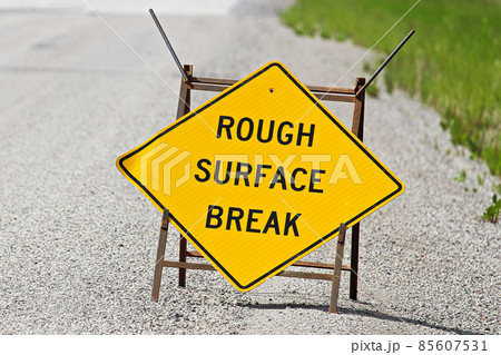Closeup of a yellow rough surface break sign on pavement Closeup of a yellow rough surface break sign on pavement 85607531