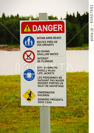 A beach danger sign with rules in both english and french A beach danger sign with rules in both english and french 85607691