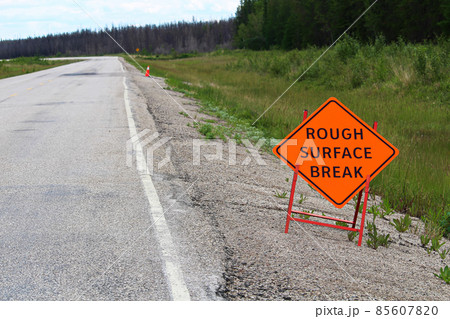 An orange rough surface break sign with a road into the distance An orange rough surface break sign with a road into the distance 85607820