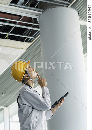 タブレットを持ってビル天井の破損箇所を調査する作業服姿の男性 タブレットを持ってビル天井の破損箇所を調査する作業服姿の男性 85610944