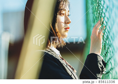 フェンスの前で佇む女子高生 85611336