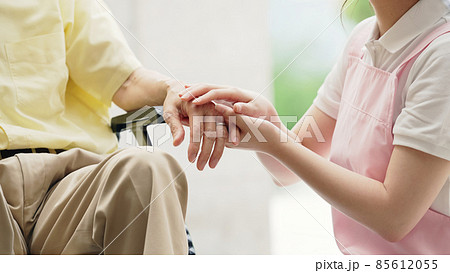 車いすに乗ったお年寄りと話す介護ヘルパー 85612055