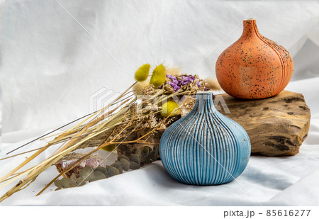 Two beautiful small ceramic vases with wooden logs on white background. Two beautiful small ceramic vases with wooden logs on white background. 85616277