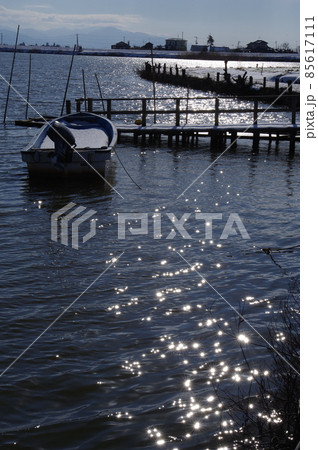 冬の福島潟 小舟とキラキラ光る太陽の水面反射 冬の福島潟 小舟とキラキラ光る太陽の水面反射 85617111