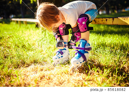 Cute girl dresses roller skates while sitting on the bench. Active healthy lifestyle. safe riding 85618082