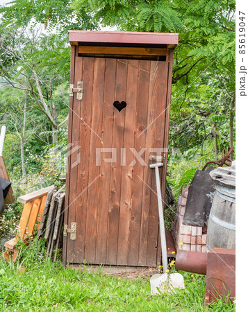 Small wooden outdoors toilet with carved heart in garden. Small wooden outdoors toilet with carved heart in garden. 85619047