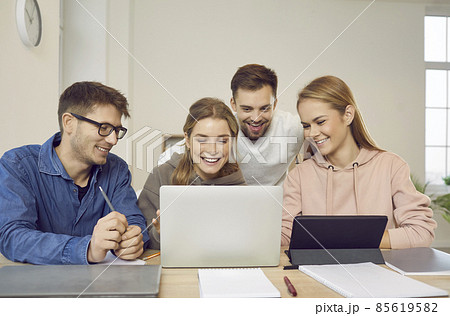 Group of happy creative university students sitting at table, looking at modern laptop computer, talking, discussing business ideas, making web marketing presentation together. Education concept Group of happy creative university students sitting at table, looking at modern laptop computer, talking, discussing business ideas, making web marketing presentation together. Education concept 85619582