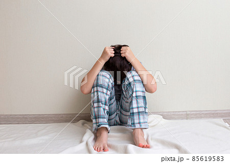 Teen boy in pajamas sitting on the floor Teen boy in pajamas sitting on the floor 85619583