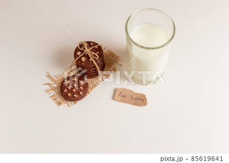 on a white table, a stack of chocolate chip cookies, a glass of milk on a white table, a stack of chocolate chip cookies, a glass of milk 85619641