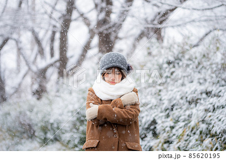 雪の降る冬の屋外で寒さに凍える女性 85620195