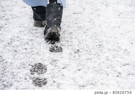 雪の積もった道路の上を歩く女性の足元の写真素材