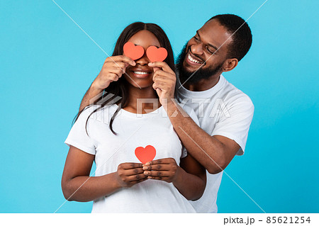 Young Romantic Black Couple Covering Eyes With Red Paper Hearts Young Romantic Black Couple Covering Eyes With Red Paper Hearts 85621254