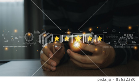 Close up man using mobile phone for rating feedback from customer service with annual survey with five gold star icon. Business annual satisfaction survey concept. User reviews and feedback online. 85622230