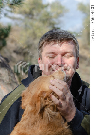Portrait of a red mixed breed dog and a mature male. Portrait of a red mixed breed dog and a mature male. 85624601