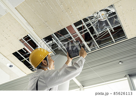 タブレットでビル天井の破損箇所を撮影する作業服姿の男性 タブレットでビル天井の破損箇所を撮影する作業服姿の男性 85626113