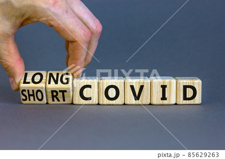 Long covid symbol. Doctor turnes wooden cubes and changes words ' long covid' to 'short covid'. Beautiful grey table, grey background, copy space. Medical, covid-19 pandemic long covid concept. Long covid symbol. Doctor turnes wooden cubes and changes words ' long covid' to 'short covid'. Beautiful grey table, grey background, copy space. Medical, covid-19 pandemic long covid concept. 85629263