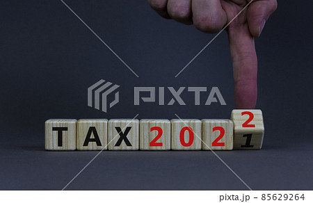 2022 tax new year symbol. Businessman turns a wooden cube and changes words Tax 2021 to Tax 2022. Beautiful grey table, grey background, copy space. Business, 2022 tax new year concept. 2022 tax new year symbol. Businessman turns a wooden cube and changes words Tax 2021 to Tax 2022. Beautiful grey table, grey background, copy space. Business, 2022 tax new year concept. 85629264
