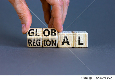 Regional or global symbol. Businessman turns wooden cubes and changes the word 'regional' to 'global'. Beautiful grey table, grey background. Business and regional or global concept. Copy space. 85629352