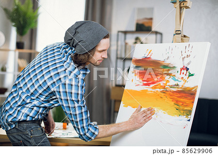 Inspired man drawing colorful pattern with hands on easel 85629906