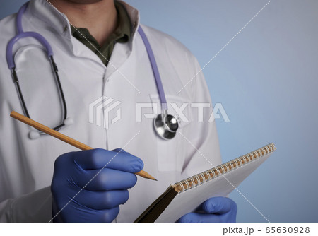 Doctor Writes Paper Log with Pencil - Photo on Blue Gradient Background Doctor Writes Paper Log with Pencil - Photo on Blue Gradient Background 85630928