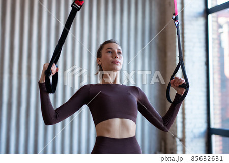 Fit woman training with fitness trx straps 85632631