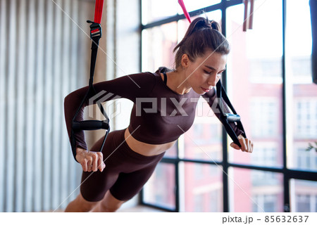 Fit woman doing push-up exercise with trx Fit woman doing push-up exercise with trx 85632637