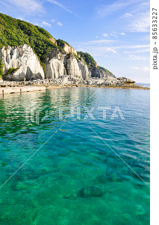 仏ヶ浦の白い崖肌が映えるエメラルドグリーンの透けて見える海と青い空 85633227