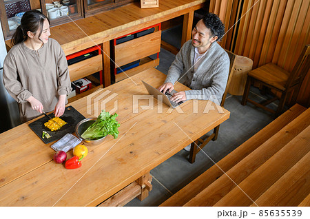 キッチンで料理するかわいい日本人女性と会話する旦那さん　俯瞰 85635539