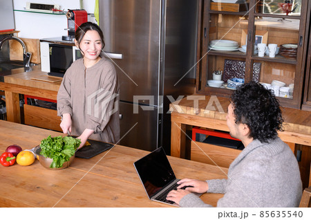 キッチンで料理するかわいい日本人女性と会話する旦那さん　俯瞰 85635540