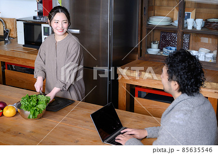 キッチンで料理するかわいい日本人女性と会話する旦那さん　俯瞰 85635546