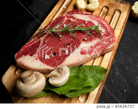 Marbled raw beef steak with seasoning on a wooden board. 85636737