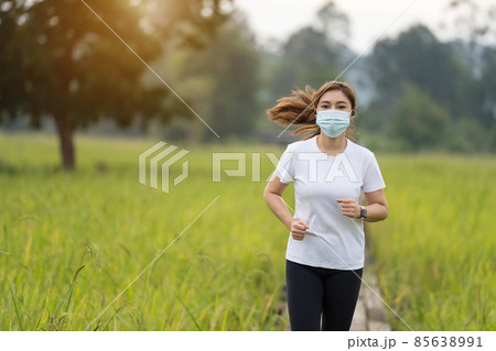woman running in field with medical mask to protect Coronavirus(Covid-19) pandemic 85638991