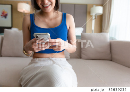 Happy asian girl checking social media holding smartphone at home. Smiling young woman using mobile phone app shopping online, ordering delivery relax on sofa. Happy asian girl checking social media holding smartphone at home. Smiling young woman using mobile phone app shopping online, ordering delivery relax on sofa. 85639235