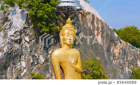 Aerial view of Phra Putthachai Tham Rusi Khao Ngu, golden buddha pagoda stupa, Ratchaburi, Thailand with green mountain hills and forest trees. Thai buddhist temple architecture. Tourist attraction. Aerial view of Phra Putthachai Tham Rusi Khao Ngu, golden buddha pagoda stupa, Ratchaburi, Thailand with green mountain hills and forest trees. Thai buddhist temple architecture. Tourist attraction. 85640089