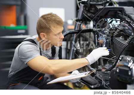 A man in the garage is checking a motorcycle 85640466