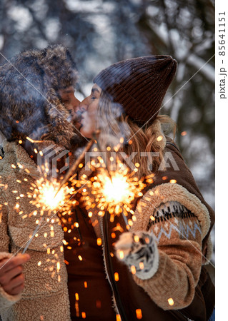 Couple Love Story in Snow Forest Kissing and Holding Sparklers. Couple in Winter Nature. Couple Celebrating. Valentine's day date. Couple Love Story in Snow Forest Kissing and Holding Sparklers. Couple in Winter Nature. Couple Celebrating. Valentine's day date. 85641151