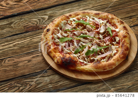 neapolitan Pizza with Mozzarella cheese, bacon, ham, tomato sauce, chicken, Spices and Fresh arugula. Italian pizza on wooden table background neapolitan Pizza with Mozzarella cheese, bacon, ham, tomato sauce, chicken, Spices and Fresh arugula. Italian pizza on wooden table background 85641278