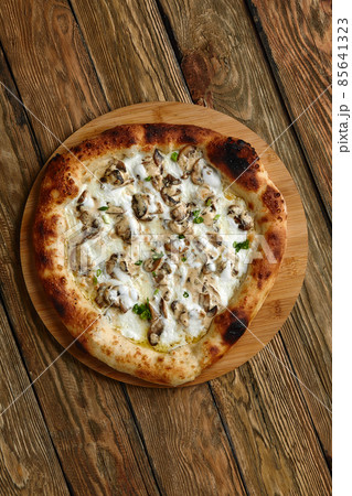 Mushroom pizza, pizza with addition of edible forest mushrooms porcini mushrooms, chanterelle and mozzarella cheese and herbs on a wooden rustic table 85641323