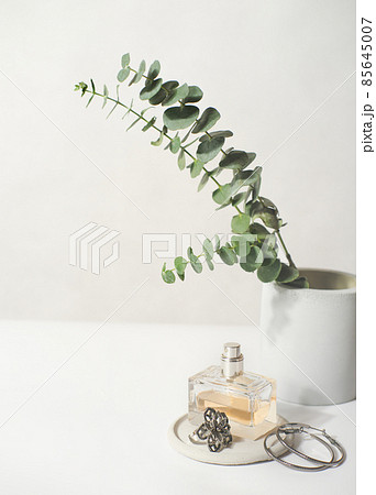 a bottle of perfume and jewelry on a concrete plate. beauty acsessories for woman. female bed table decor. modern earrings and ring. copy space. 85645007