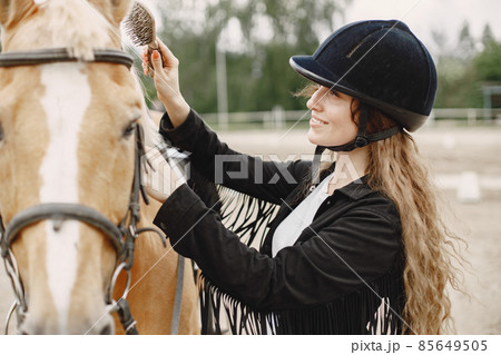 Portrait of riding horse with woman in black helmet with comb Portrait of riding horse with woman in black helmet with comb 85649505