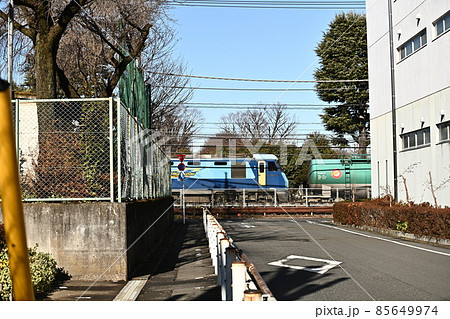 道路の先に見える貨物列車　白い建物と青空に電気機関車のブルーが映える　 85649974