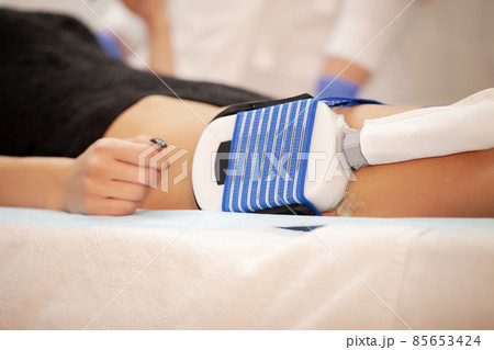 The procedure of myostimulation on the legs of a woman in a beauty salon. The procedure of myostimulation on the legs of a woman in a beauty salon. 85653424