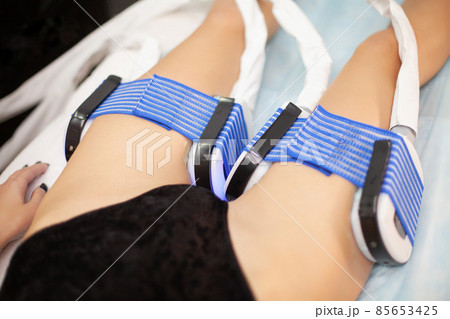 The procedure of myostimulation on the legs of a woman in a beauty salon. The procedure of myostimulation on the legs of a woman in a beauty salon. 85653425