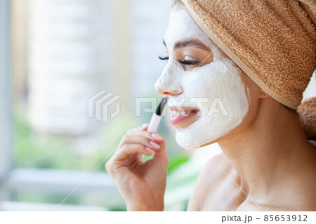 Beautiful young woman applying facial mask on her face. Beautiful young woman applying facial mask on her face. 85653912