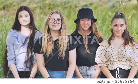 Girls cover their faces with a toy Pop It while sitting in the park. 85655364