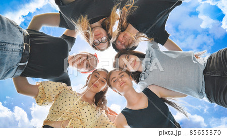 Happy girls friends hugging in a circle on the background of the fairy sky. 85655370