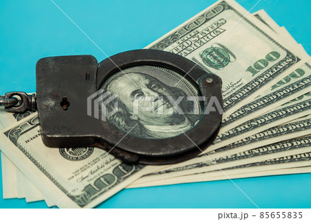 Handcuffs for money. Close-up of handcuffs on a hundred banknotes. Handcuffs on the background of Handcuffs for money. Close-up of handcuffs on a hundred banknotes. Handcuffs on the background of 85655835