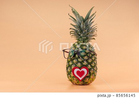 Interpretation of pineapple fruit in human image with glasses and heart concept of medicine or Valentine's day lovers. Copy space on yellow background 85656145