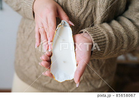 Close-up cropped shot of unrecognizable young woman holding beautifulhandmade candle in candlestick made of exotic seashell. Close-up cropped shot of unrecognizable young woman holding beautifulhandmade candle in candlestick made of exotic seashell. 85658067