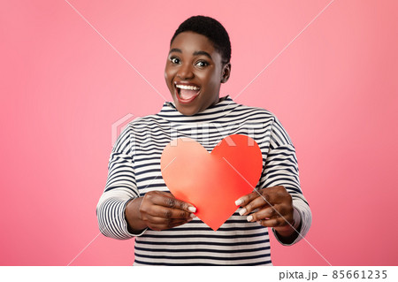 Cheerful Overweight Black Lady Showing Red Paper Heart, Pink Background Cheerful Overweight Black Lady Showing Red Paper Heart, Pink Background 85661235